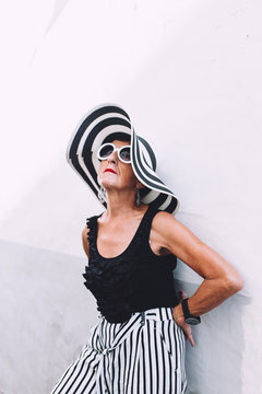 Mature woman with striped sun hat posing in the street