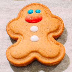 Homemade Christmas bakery close up. Festive background of smiling gingerbread man on cooking sheet. Family celebration and New Year traditions concept