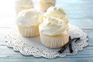 Tasty vanilla cupcakes on wooden table