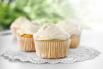 Tasty vanilla cupcakes on table