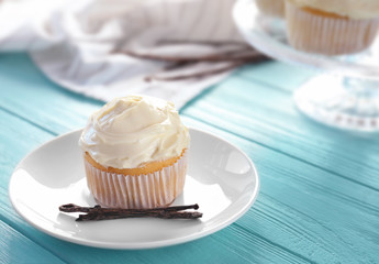 Plate with tasty vanilla cupcake on table