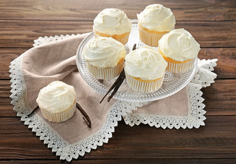 Dessert stand with tasty vanilla cupcakes on wooden table