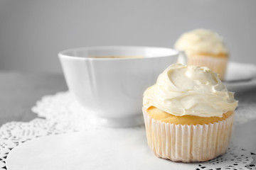 Tasty vanilla cupcake and cup on table