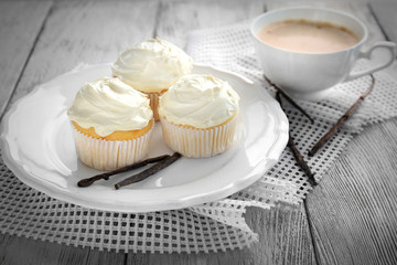 Tasty vanilla cupcakes and cup of coffee on table