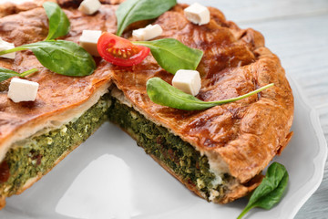 Tasty sliced pie with spinach on plate, close up