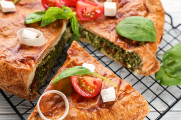 Tasty pie with spinach on metal grid, close up