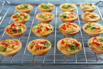 Baking grid with broccoli quiche tartlets on table