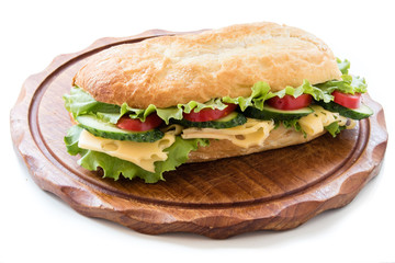 Ciabatta sandwich with salad, tomato, cucumber and cheese on wooden board