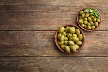 Bowls with healthy olives on wooden table