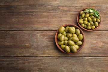 Bowls with healthy olives on wooden table