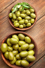 Bowls with healthy olives on wooden table