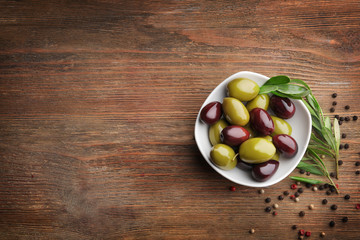 Bowl with olives on wooden table