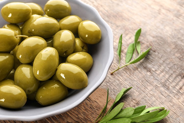 Bowl with olives on wooden table