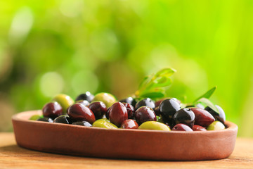 Plate with different olives on wooden table