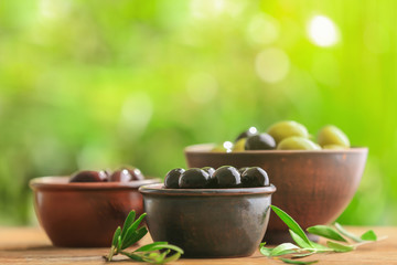 Bowls with healthy olives on blurred background