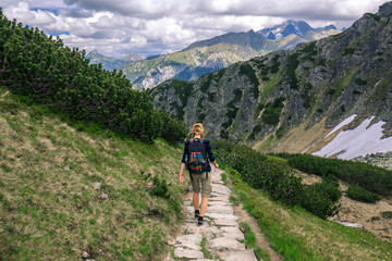 Fototapeta na wymiar GIrl with backpack trekking on the rocky path in Tatra mountains, Poland