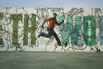 Man jumping in front of a graffiti wall