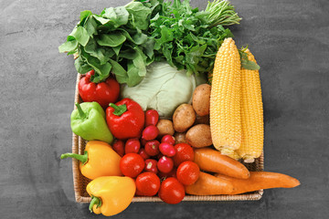 Box with fresh vegetables on grey background