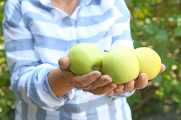 Female farmer holding fresh apples outdoors