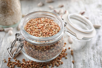 Jar with buckwheat grains on wooden table