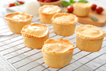 Delicious meat mini pies on baking grid, closeup