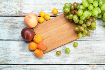 Composition with fresh fruits and kitchen board on wooden background