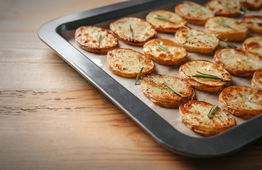 Baking tray with delicious baked potatoes on table