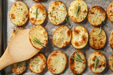 Baking tray with spatula and delicious baked potatoes, close up