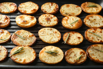 Grill pan with delicious baked potato slices, close up