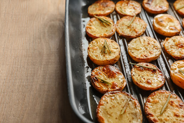 Grill pan with delicious baked potato slices on table