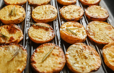 Grill pan with delicious baked potato slices, close up