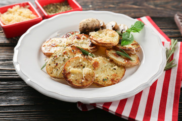 Plate with delicious baked potatoes on table