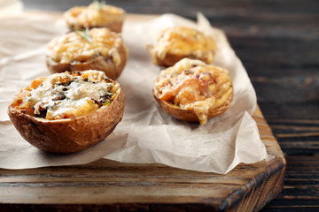 Baked stuffed potatoes on wooden board, close up