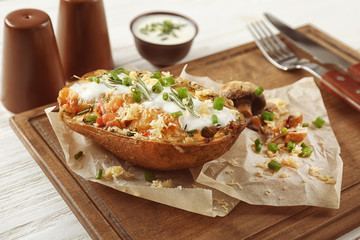 Baked stuffed potato on wooden board, close up
