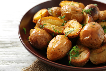 Plate with delicious baked potatoes on table, close up