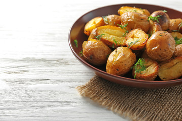 Plate with delicious baked potatoes on table