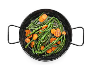 Delicious green beans and carrot slices in frying pan on white background