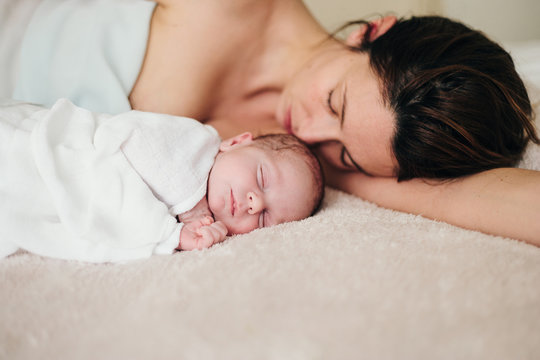 Mother and baby cuddling on bed