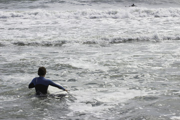 un surfista entra in mare con la muta in inverno