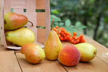 Pears, peach and rowan berries in a wooden box on a wooden table when harvesting in the forest