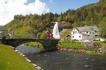 Steinsdalsfossen waterfall in the river of Steine - scenic landscape with cascade surounded by mountains and traditional norvegian, scandinavian houses