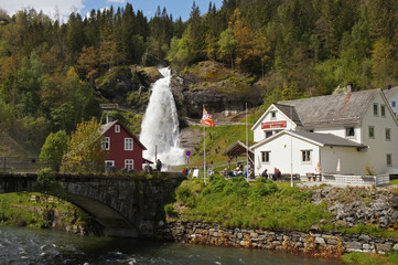 Steinsdalsfossen waterfall in the river of Steine - scenic landscape with cascade surounded by mountains and traditional norvegian, scandinavian houses