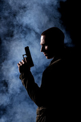 detective or criminal with gun on foggy night background