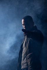 detective or criminal with gun on foggy night background