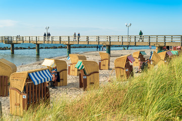 The northeastern seaside resort Wustrow at the baltic sea in Germany. The popular village on the Darss, Fish Land, with the white sandy beach and the picturesque  roofed wicker beach chairs