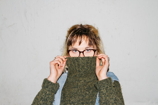female teen woman girl hides under turtle neck sweater collar