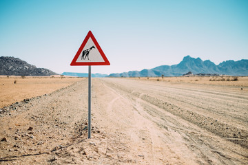 empty desert road with a yield for Giraffes sign post
