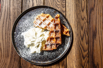 Viennese waffles with berry sauce and creme fraiche are on the plate.