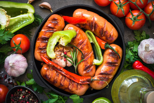 Fried bbq sausages with  vegetables at black slate table.