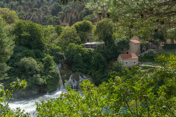 Fototapeta na wymiar Ansicht aus dem Nationalpark Krka mit kleinen Gebäuden und Wasserfall